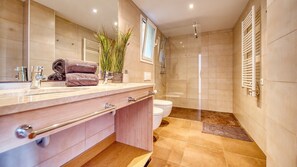 A modern bathroom with a large mirror, a sink, a toilet, and a shower area.
