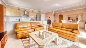 Ein Wohnzimmer mit zwei Sofas, einem Couchtisch und einer Küchenzeile mit Schränken und Geräten.