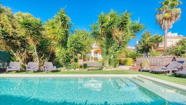 A swimming pool with lounge chairs, palm trees, and a building in the background. - Villa "Costacabana - Summertime" with Private Pool & Wi-Fi (Lloret de Mar)
