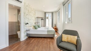 Ein Schlafzimmer mit Bett, Sessel, Nachttisch und Fenster.