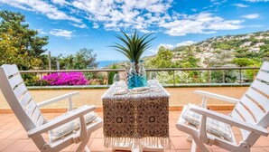 A terrace with two white chairs, a patterned table, and a potted plant. - Villa "Costacabana -  Cleo" with Sea View, Private Pool & Wi-Fi (lloret de mar)