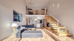 A spacious living area with a sofa, a coffee table, a staircase, and a dining area. - Holiday Home "Costacabana - Casa Adora" with Mountain View, Shared Pool & Wi-Fi (Tossa de Mar)