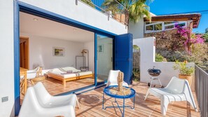 A modern outdoor living area with a bed, lounge chairs, and a barbecue. - Holiday Home "Costacabana - Casa Adora" with Mountain View, Shared Pool & Wi-Fi (Tossa de Mar)