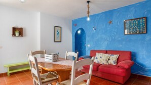 Un coin repas avec une table en bois, des chaises, un canapé rouge et un mur d’accent bleu.