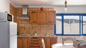 Une cuisine dotée de meubles en bois, d’un four à micro-ondes, d’un évier et d’un coin repas avec une table et des chaises.