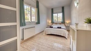 Ein Schlafzimmer mit einem Bett, zwei Nachttischen, einem Heizkörper und einem Fenster mit Vorhängen.