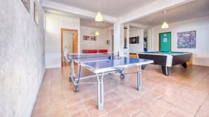 A room with a ping pong table, a pool table, and a door leading to a bathroom.