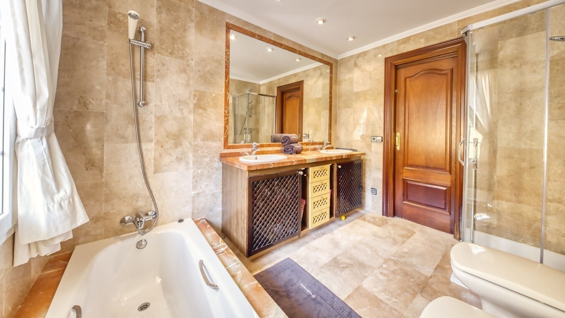 Une salle de bain comprenant une baignoire, une douche, un meuble-lavabo avec un miroir et des toilettes.