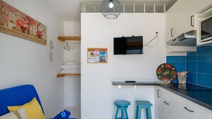A compact living space with a sofa, two stools, a TV, and a kitchen area with a microwave. - Vacation Studio 'Loft La Caletilla' with Sea View and Private Terrace (Caleta de Sebo)