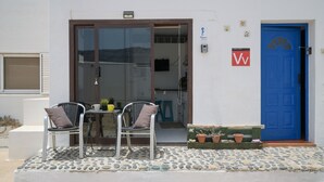 A building with a blue door, a glass door entrance, two chairs with cushions, a small table, and potted plants. - Vacation Studio 'Loft La Caletilla' with Sea View and Private Terrace (Caleta de Sebo)
