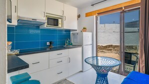 A compact kitchen with white cabinets, a blue tiled backsplash, a microwave, and a refrigerator. - Vacation Studio 'Loft La Caletilla' with Sea View and Private Terrace (Caleta de Sebo)