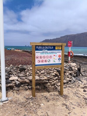 Un letrero de playa con instrucciones de seguridad y un salvavidas.