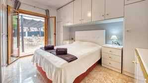 Une chambre d’hôtel comprenant un lit, une table de chevet, une lampe, une porte-fenêtre coulissante donnant sur un espace extérieur et un mini-bar.