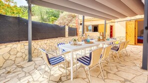 An outdoor patio with a stone floor, white table, and striped chairs.