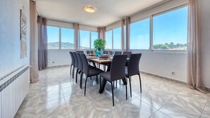 A dining area with a table set for six, large windows, and a view of the landscape. - Villa "Costacabana - Abigail" with Sea View, Private Pool & Wi-Fi (Lloret De Mar)