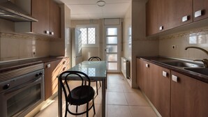 A kitchen with wooden cabinets, a stainless steel sink, and a dining table with chairs. - Villa "Costacabana - Yara" with Private Pool & Wi-Fi (Lloret De Mar)