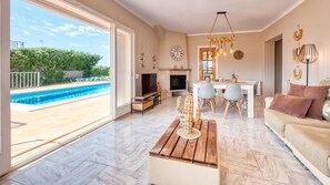 Ein geräumiges Wohnzimmer mit großem Fenster, Pool, Essbereich und Kamin.