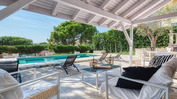Zona de piscina exterior con sillones de descanso y una pérgola.