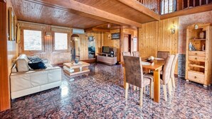Un interior de madera con un sofá, una mesa de comedor, sillas y un televisor.