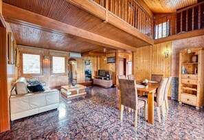 Un intérieur en bois comprenant un canapé, une table à manger, des chaises et un téléviseur.