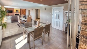 Un espacio habitable amplio con una mesa de comedor, sillas de mimbre, una chimenea y una cocina moderna al fondo.