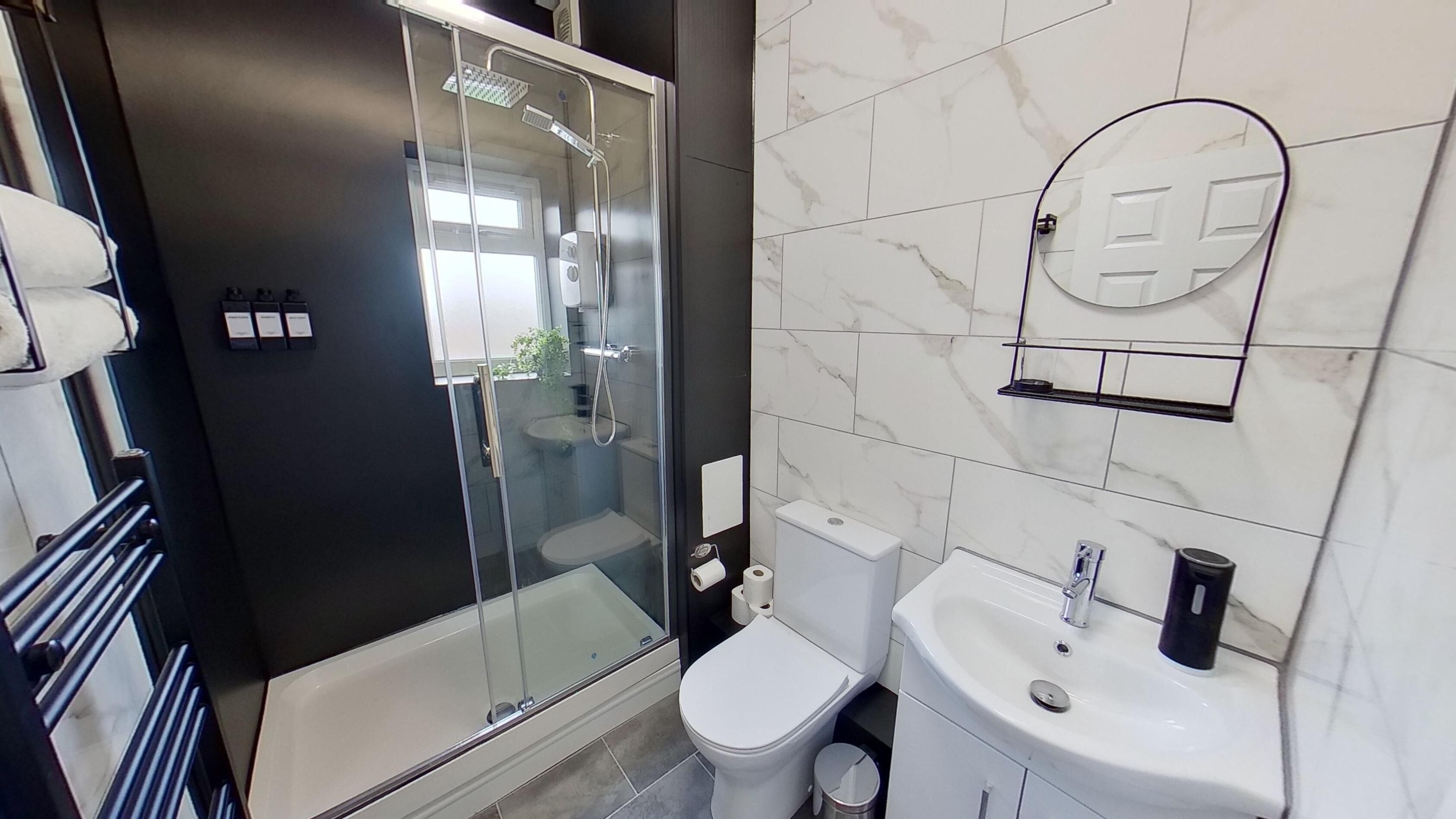 Un bagno moderno con doccia vetrata, servizi igienici e lavandino.