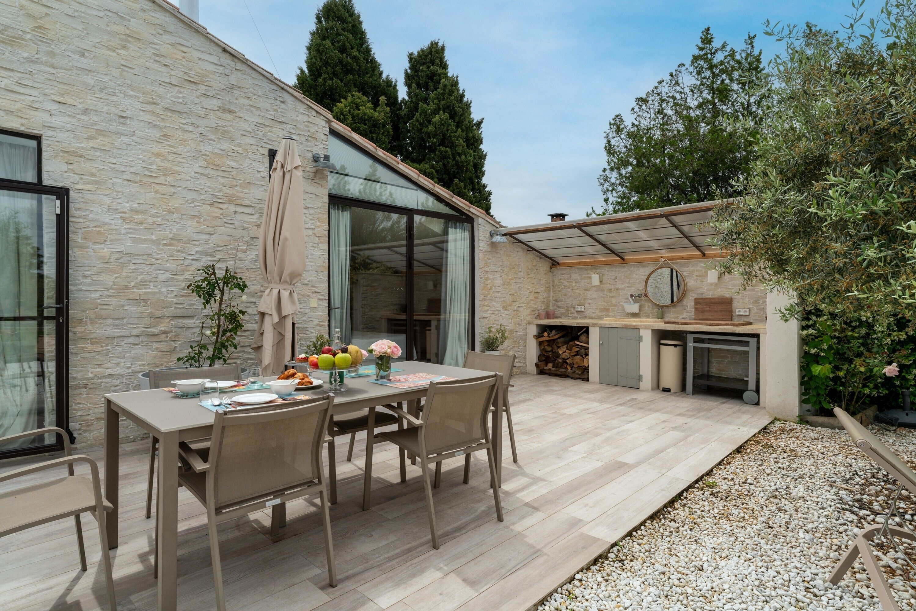 A patio with a table set for dining, a grill area, and a stone wall.
