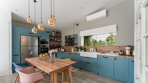 A modern kitchen with blue cabinets, a wooden dining table, and pendant lights. - Holiday Home "Le Cabanon de Modène" with Mountain View, Wi-Fi and Air Conditioning (Modène)