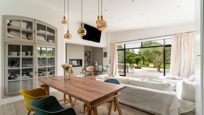 A modern living room with a wooden dining table, colorful chairs, a white sofa, and a large window with a view of the outdoors. - Holiday Home "Le Cabanon de Modène" with Mountain View, Wi-Fi and Air Conditioning (Modène)