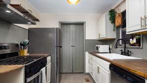 Eine moderne Küche mit Edelstahlgeräten, weißen Schränken und einer Holz Arbeitsplatte.