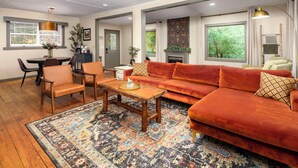 Ein Wohnzimmer mit einem roten Sofa, einem Holztisch und einem gemusterten Teppich.