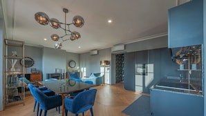 A modern dining area with a wooden table, blue chairs, and a unique chandelier. - Apartments Florence - Repubblica Exclusive with Balcony (Florence)