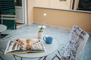 Uma mesa com um livro, uma xícara de café e um vaso de flores.