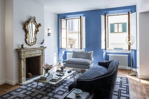 A living room with a fireplace, patterned sofa, and a coffee table. - Apartments Florence - Blue Lily with terrace (Firenze)