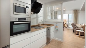 Una cocina moderna con electrodomésticos integrados, lavavajillas y ventana con vistas a un balcón.