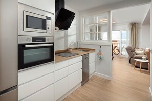 A modern kitchen with built-in appliances, a dishwasher, and a window overlooking a balcony.