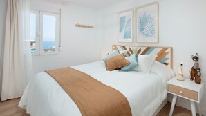 Un dormitorio con cama, mesita de noche y ventana con cortinas.