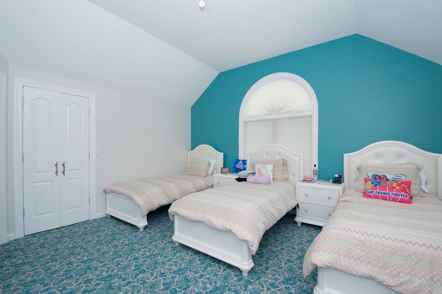 Een slaapkamer met twee bedden, een witte kast en een wand in zachtgroen.