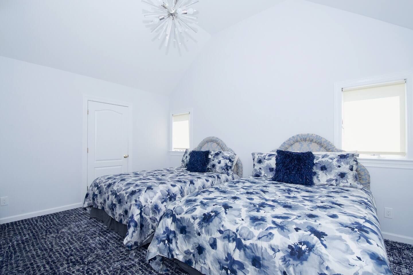 A bedroom with two beds, a white door, and a window.