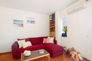 A living room with a red sofa, a coffee table, and a bookshelf. - Apartment 'Apartarment Azur' with Wi-Fi (Albufeira)