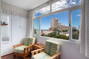 A balcony with two wooden chairs, a small table, and a view of a tall building. - Apartment 'Apartarment Azur' with Wi-Fi (Albufeira)