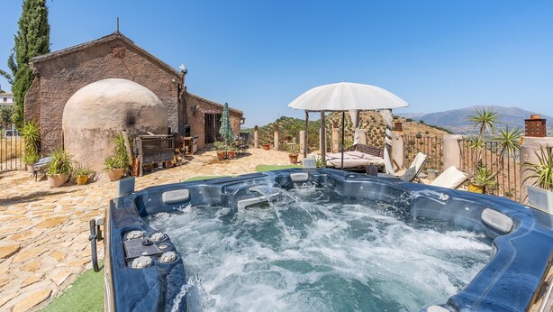 A hot tub with a stone patio, a gazebo, and a building with an arched entrance. - Holiday Home 'Ermita De Las Eras' with Mountain Views, Wi-Fi and Air Conditioning (Algarinejo)