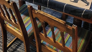 En hyggelig stue med en væg af træpanel, en grå sofa, et spisebord med en bordløber med bjørnetema og en ventilator på væggen.