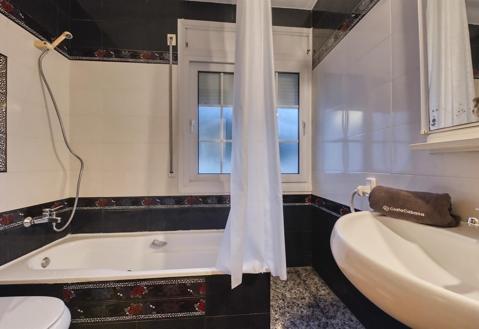 Une salle de bain avec une baignoire, un lavabo et une fenêtre donnant sur un beau paysage.