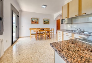Una cocina moderna con encimeras de granito, armarios de madera y una zona de comedor con mesa y sillas.