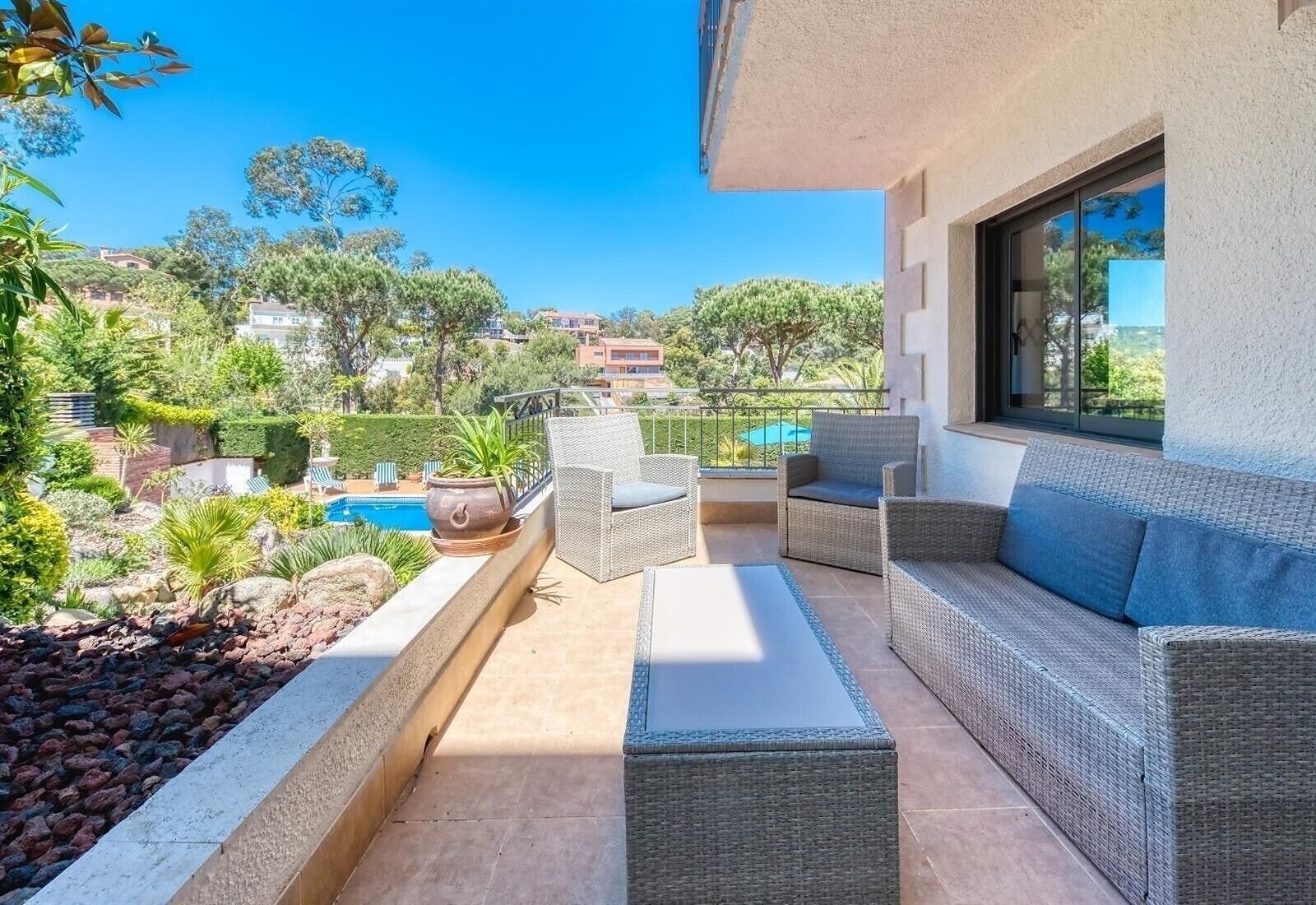 Une terrasse dotée de meubles en osier, une piscine et une vue sur le paysage environnant.