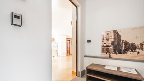 Un corridoio con una panca in legno, un quadro appeso al muro e una porta che dà su un'altra stanza.