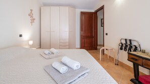 Una camera da letto con un letto, un armadio, una sedia, un tavolo e un deambulatore.