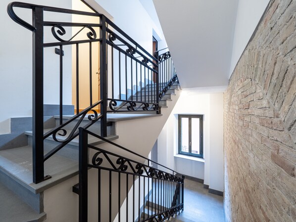 A staircase with black railings, a brick wall, and a window.
