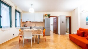 A compact living space with a dining area, kitchenette, and a sofa. - Vico 1° Sulis Apartment 3 with Wi-Fi and Air Conditioning (Cagliari)